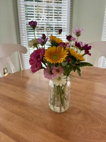 Loose arrangement of orange sunflowers and pink cosmos on a wooden table
