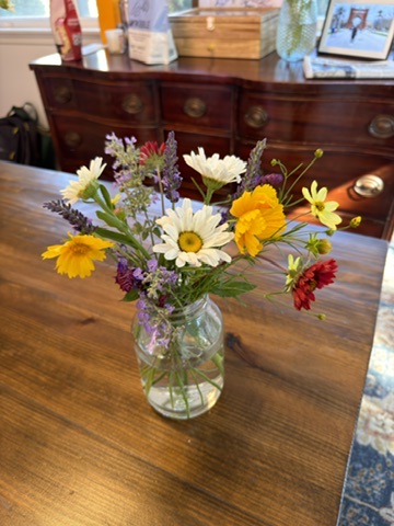 Mixed white, orange, red, and purple garden flowers in a glass jar