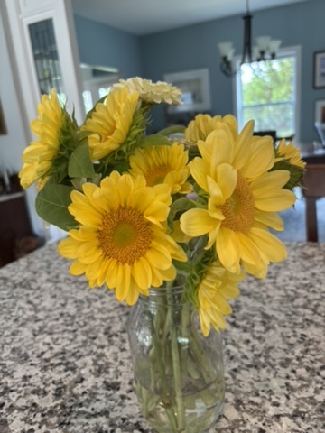 Yellow sunflowers arranged simply in a clear glass jar