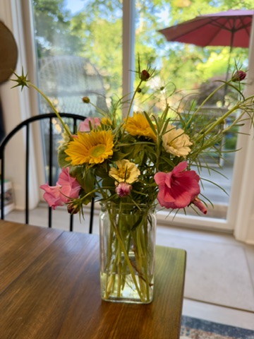 Airy pink, yellow, and orange flower arrangement beside a garden window